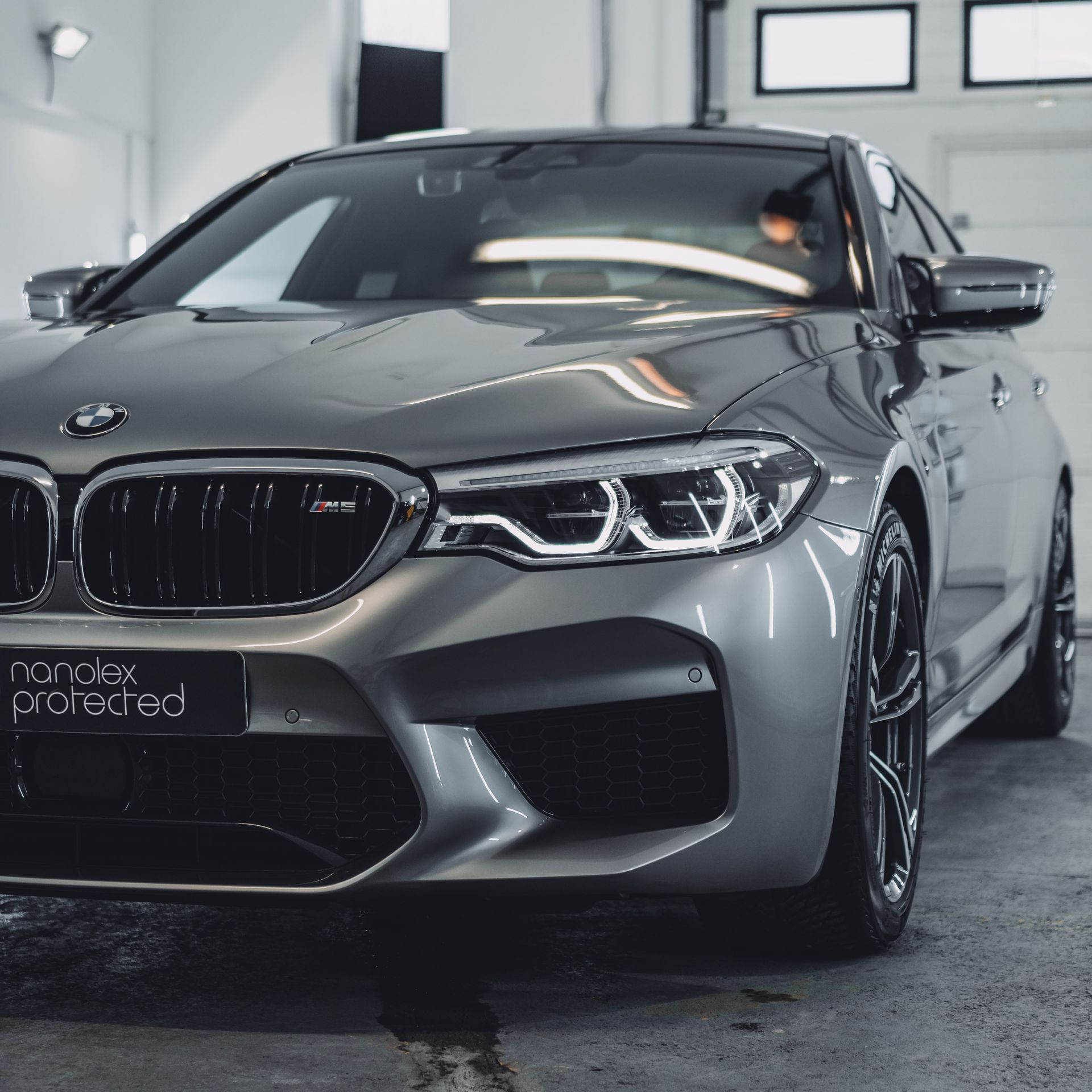 Silver BMW M5 sedan parked inside a garage, showing off a clean, detailed finish.