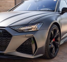 Matte gray Audi RS 6 parked outside; features black wheels, red brake calipers, and a black honeycomb grille.