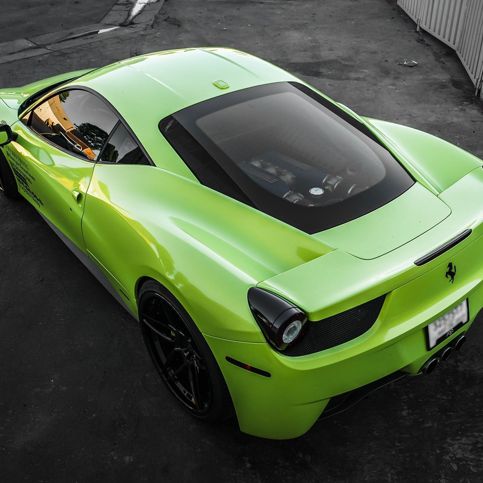 Lime green Ferrari sports car parked on a dark surface. Black wheels and a black rear diffuser are visible.