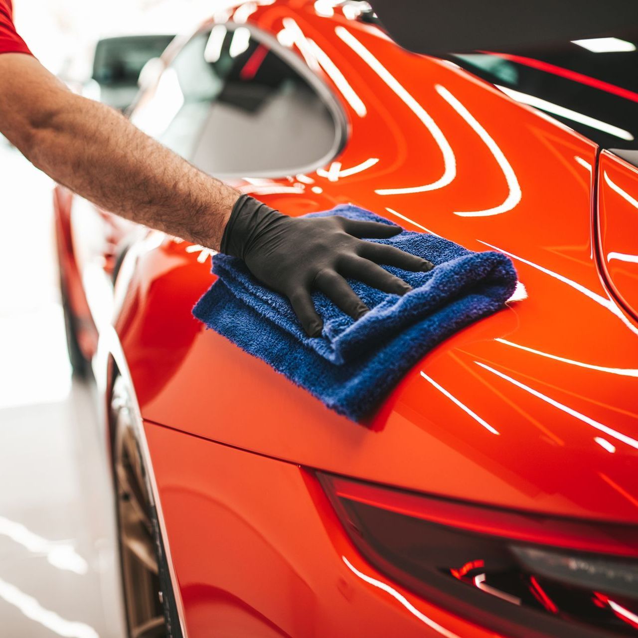 A silver sports car covered in white foam, being washed at a car wash.