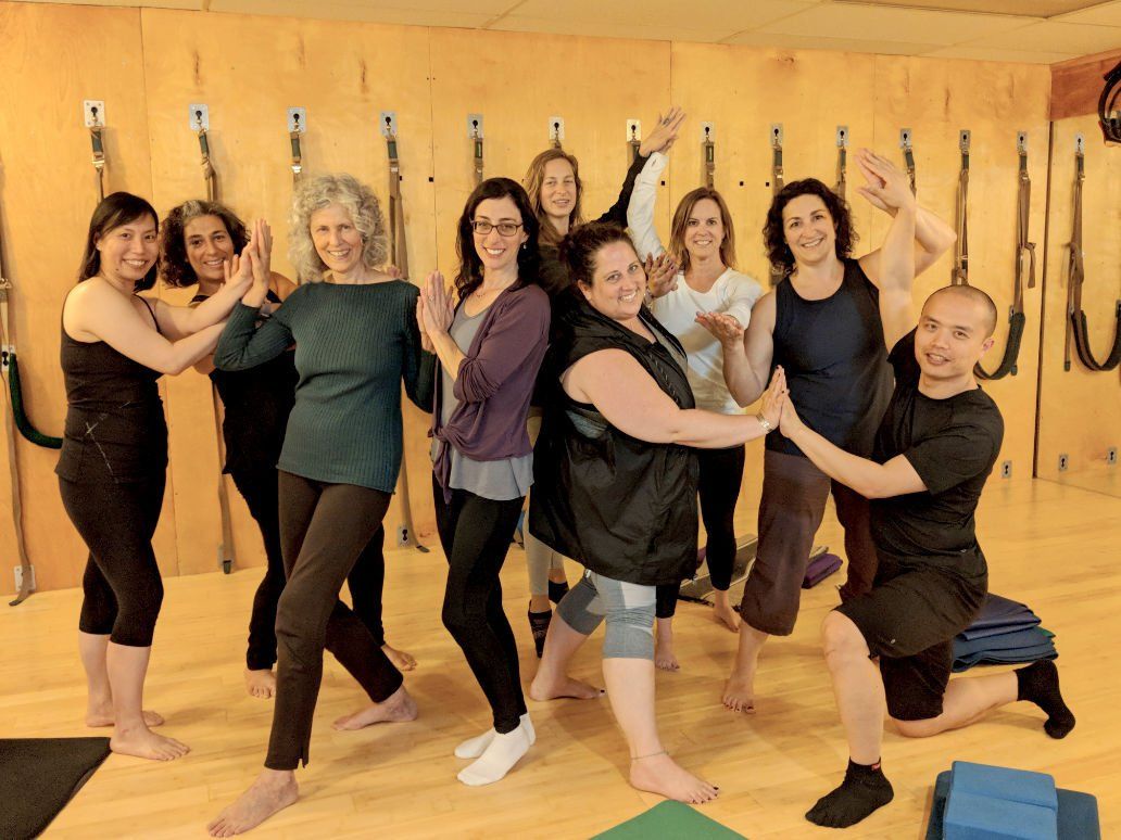 A group of people are posing for a picture in a pilates studio