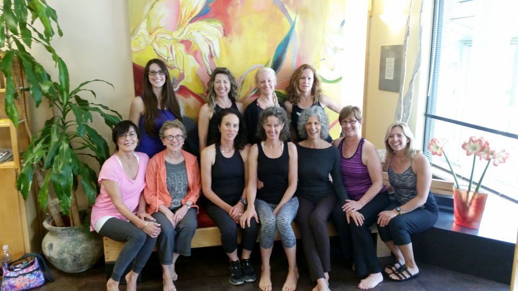 A group of women are posing for a picture in front of a painting.