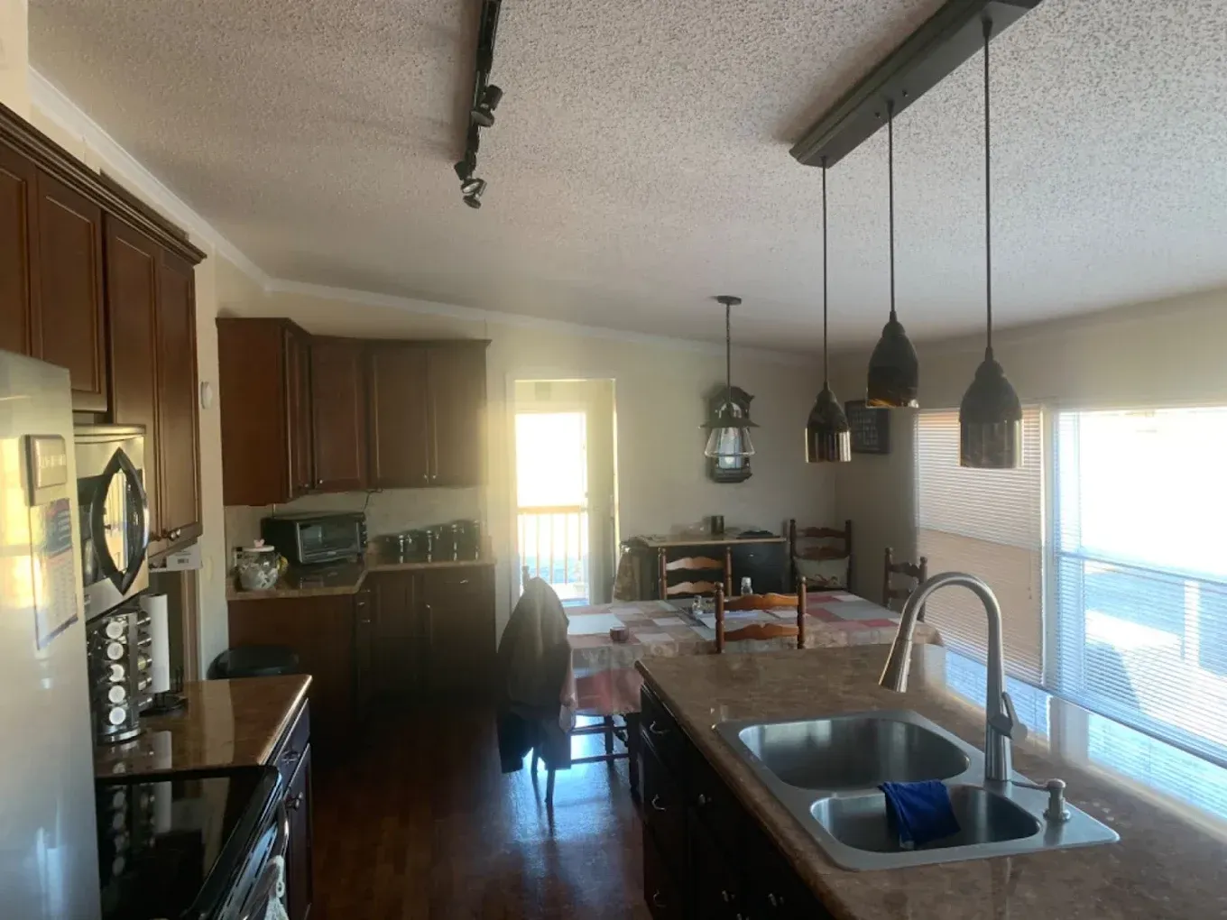 Kitchen with brown cabinets, island with sink, and pendant lights over the countertop.