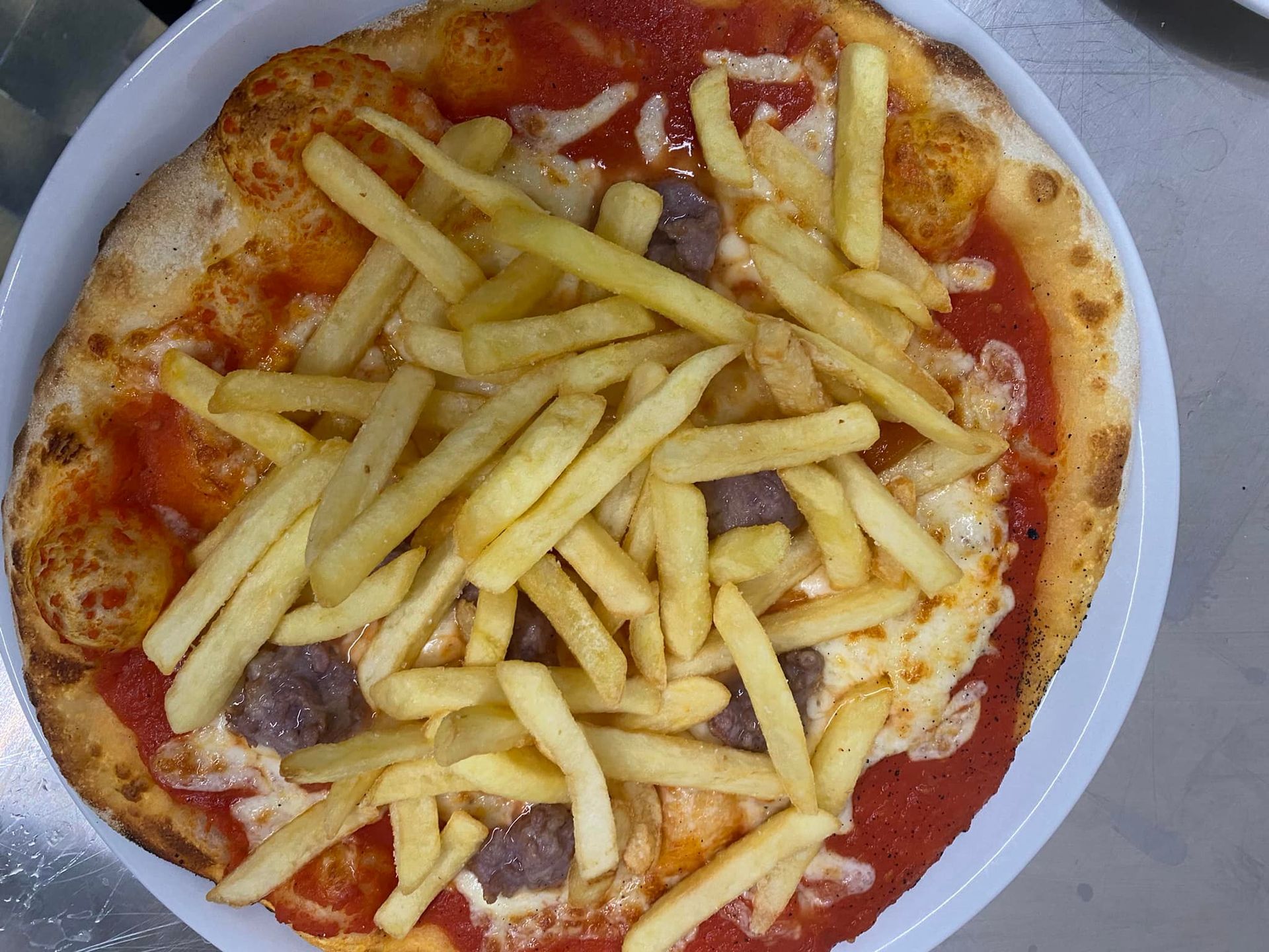 Una pizza con patatine fritte sopra su un piatto.