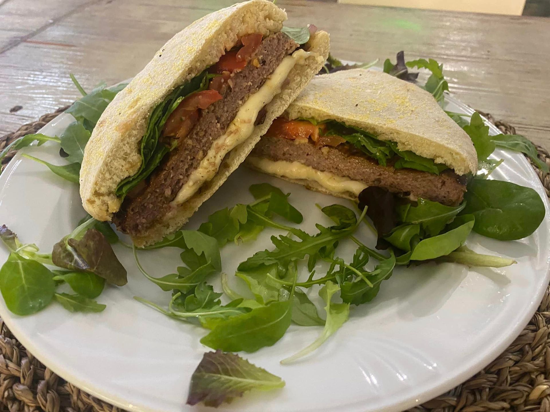 Un piatto bianco sormontato da un panino e da una lattuga su un tavolo.