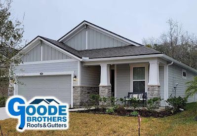 Single-story gray house with a stone base and front porch, featuring a branded Goode Brothers logo overlay.