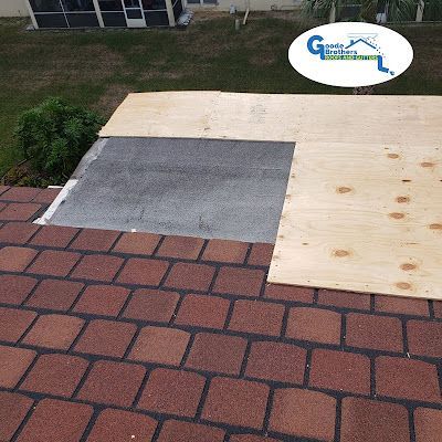 A roof under repair, showing shingles, exposed gray underlayment, and new plywood decking.