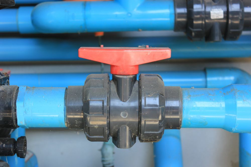 Close-up of a red-handled valve on blue and black PVC pipes — Taree Water Works in Taree, NSW