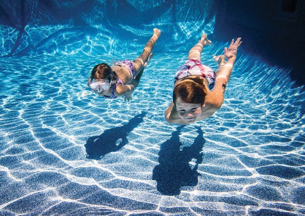 Two Children Swim Underwater in A Bright Blue Pool — Taree Water Works in Taree, NSW