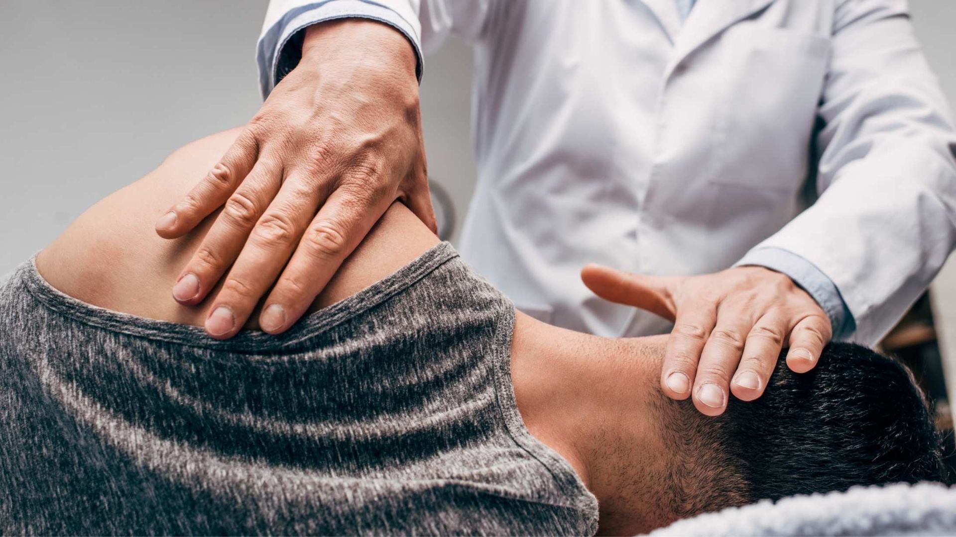 Chiropractor adjusting a patient's neck, hands on the neck and shoulder area.