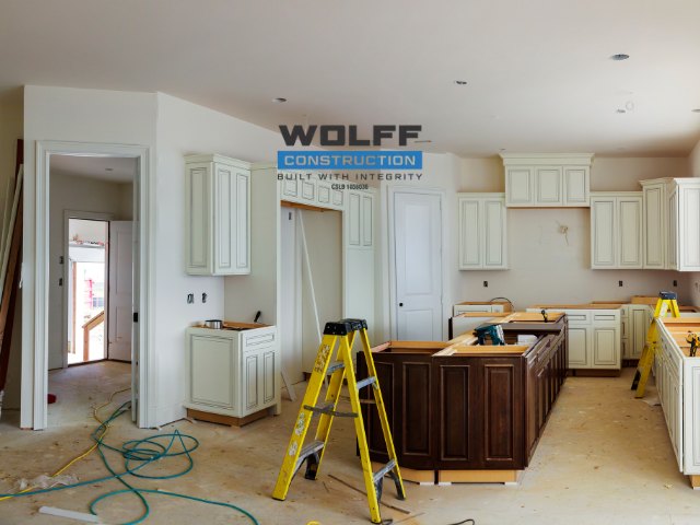 Kitchen under construction with white cabinets, brown island, and yellow ladder.