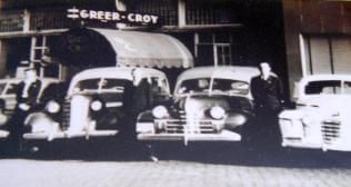A black and white photo of a row of old cars