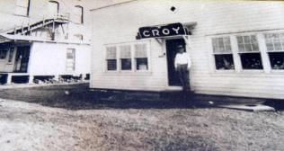 A black and white photo of a man standing in front of a building.