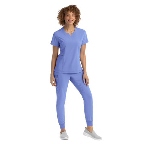 A woman is wearing a purple scrub top and pants.