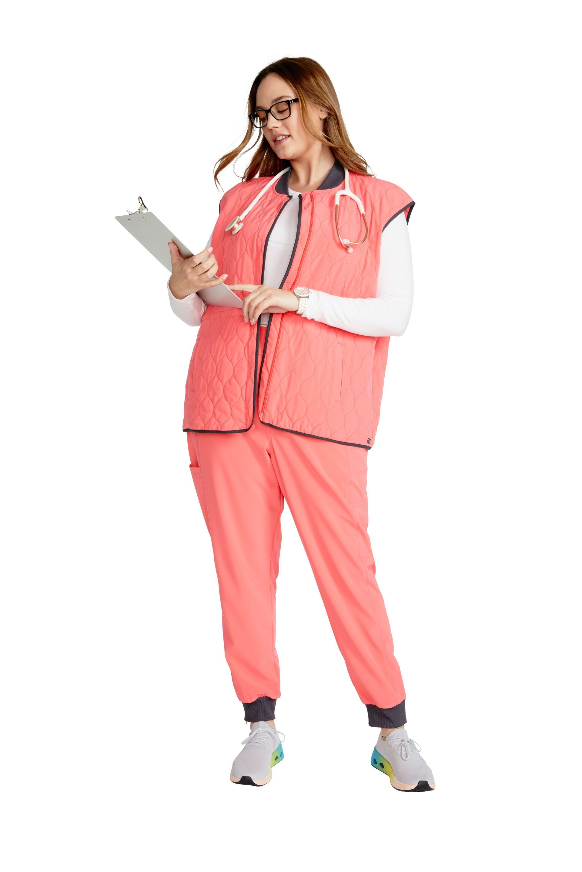 A woman in a pink scrub suit is holding a clipboard.