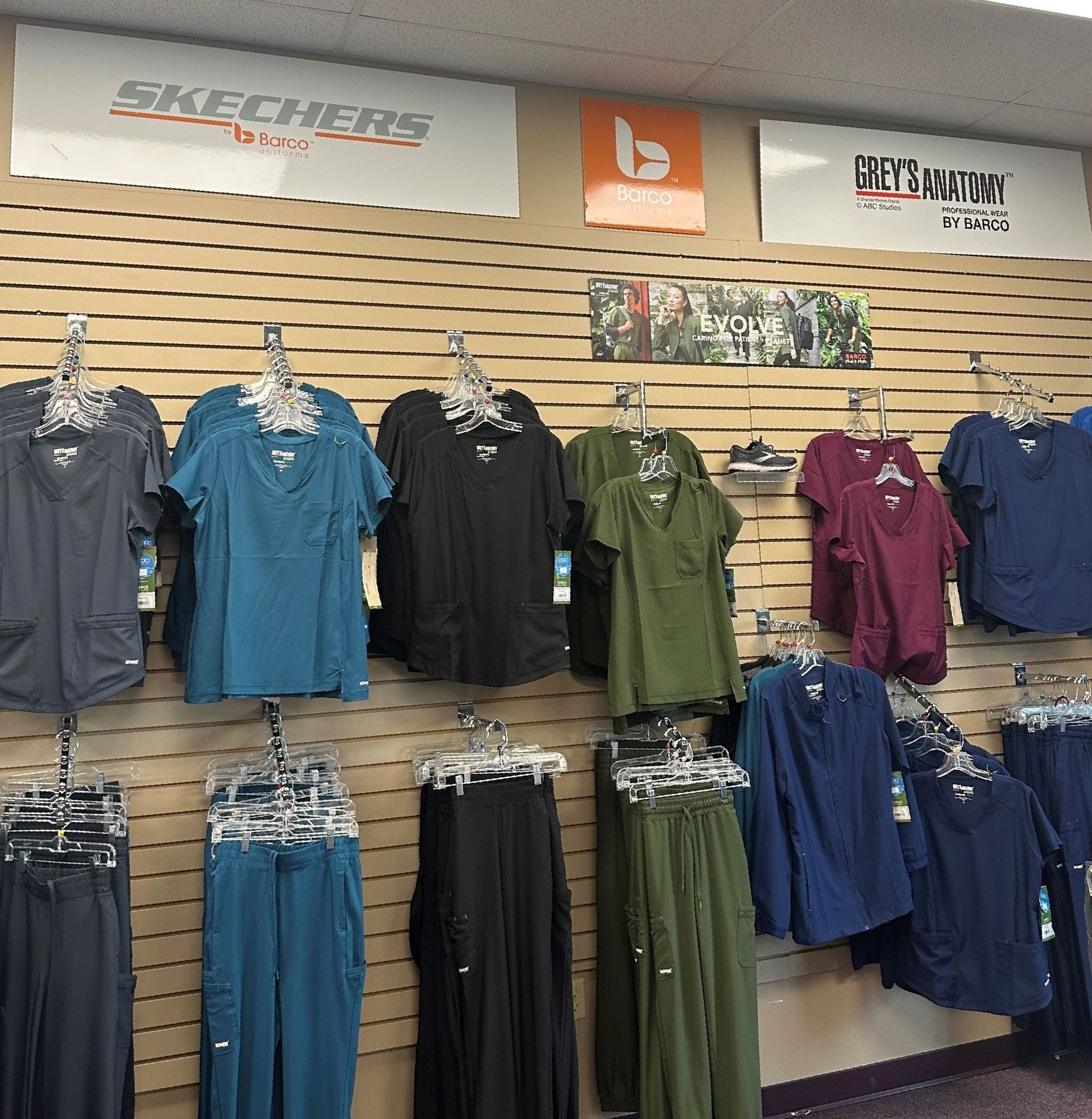 A display of scrubs in a store with a sign that says skechers