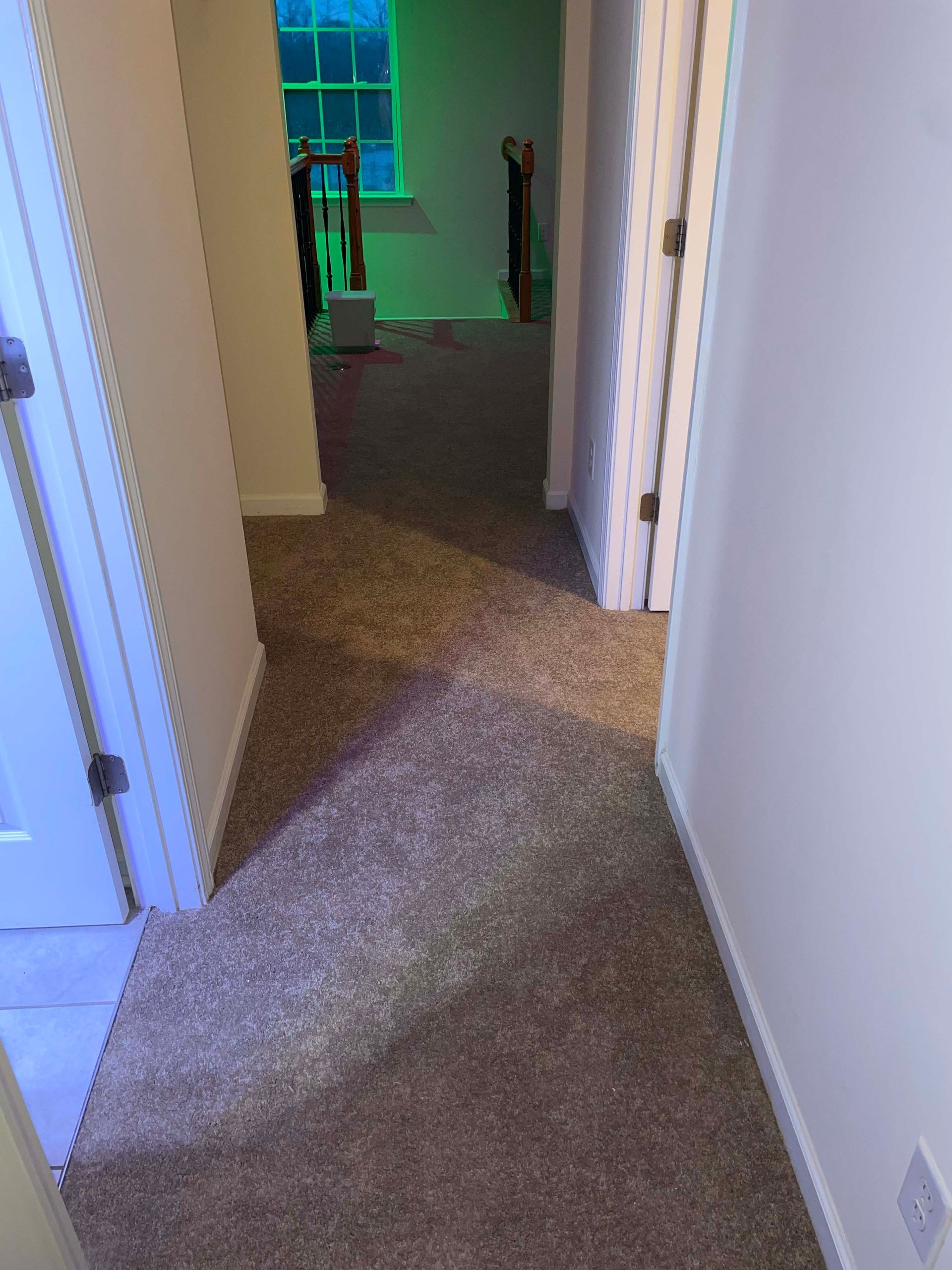 Hallway with brown carpet, white walls, and doorways leading to rooms.