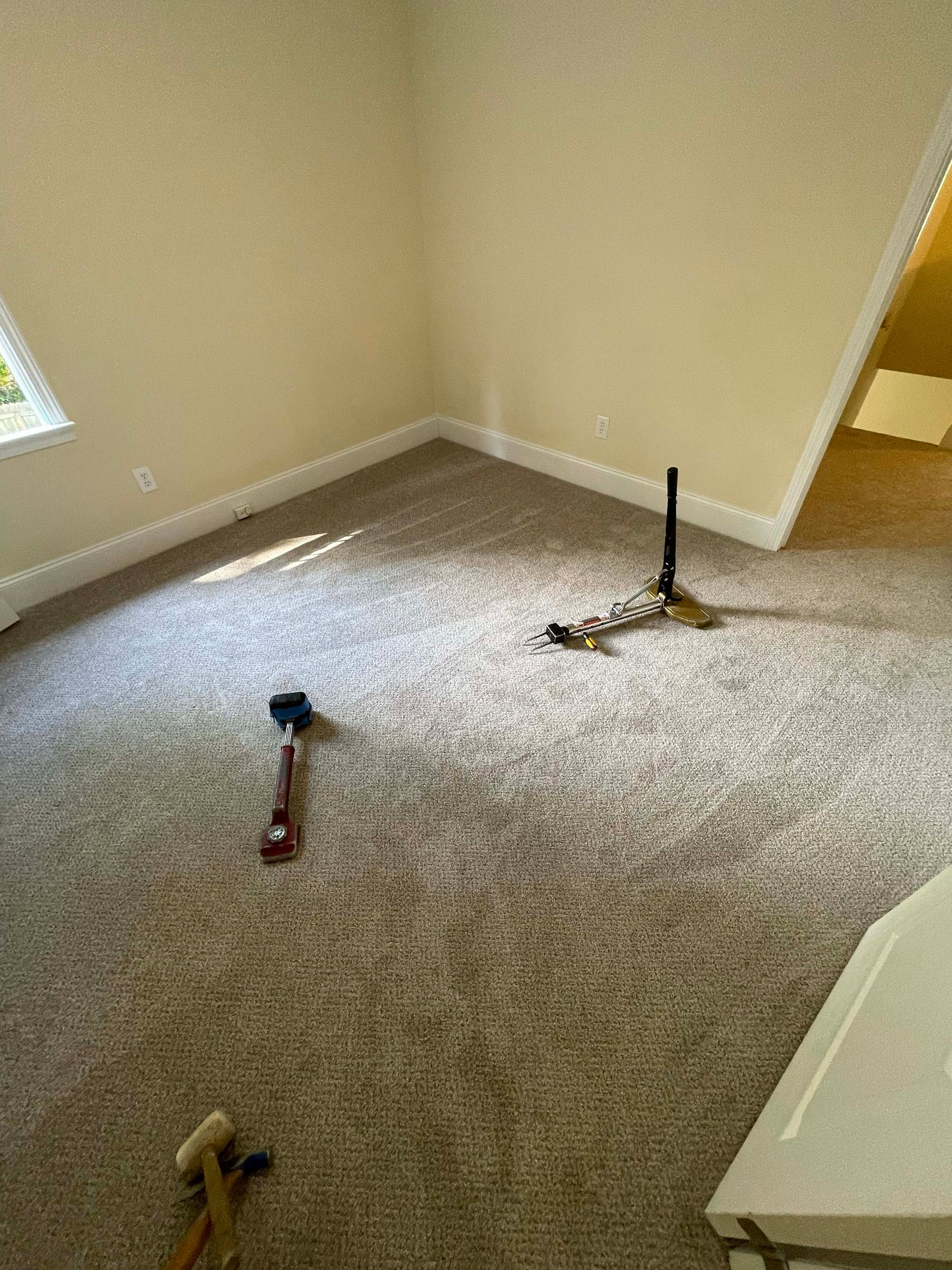 Carpeted room with beige walls and tools for carpet installation.