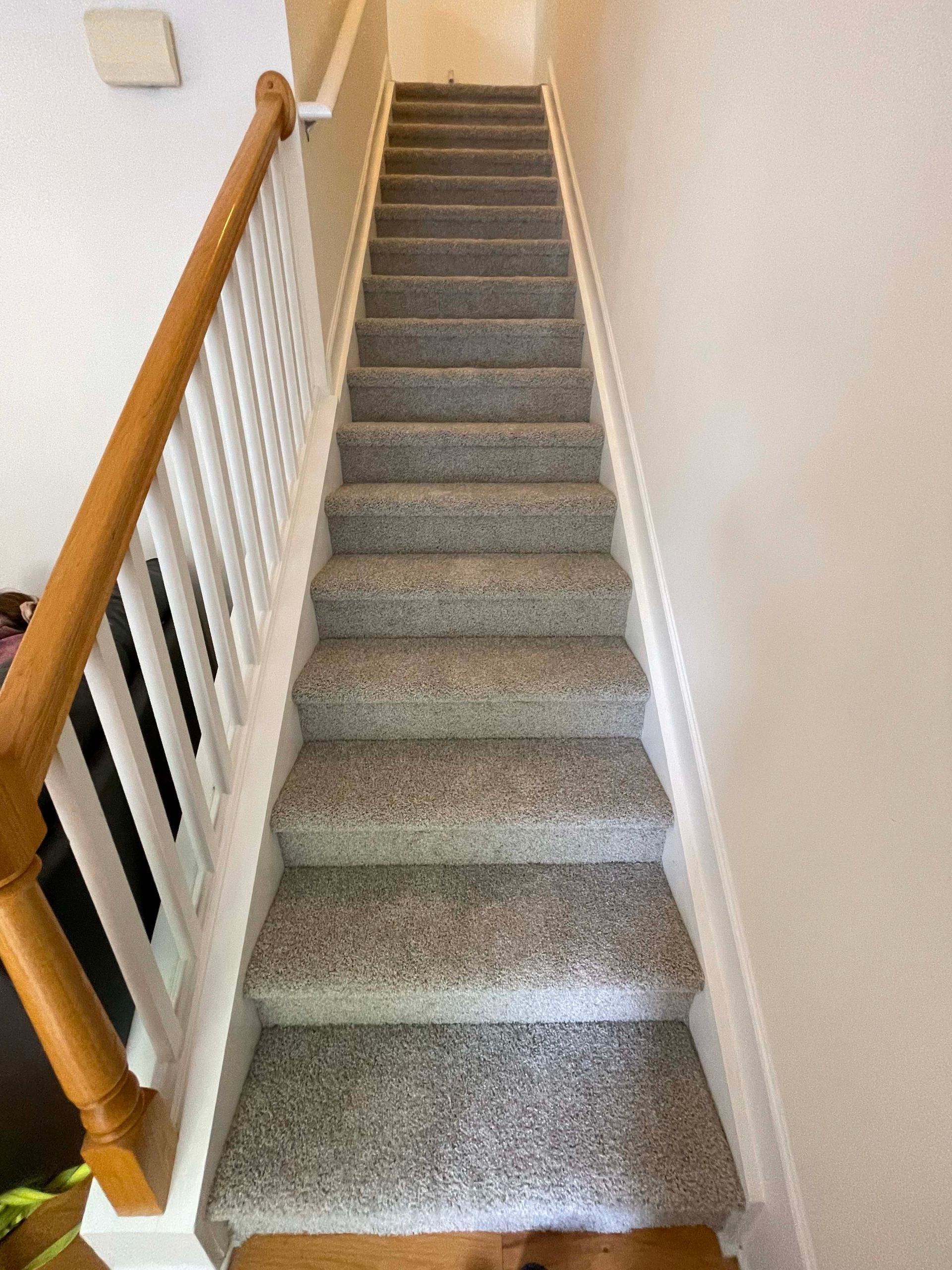 Staircase with gray carpet and white trim. Wooden banister on the left side.