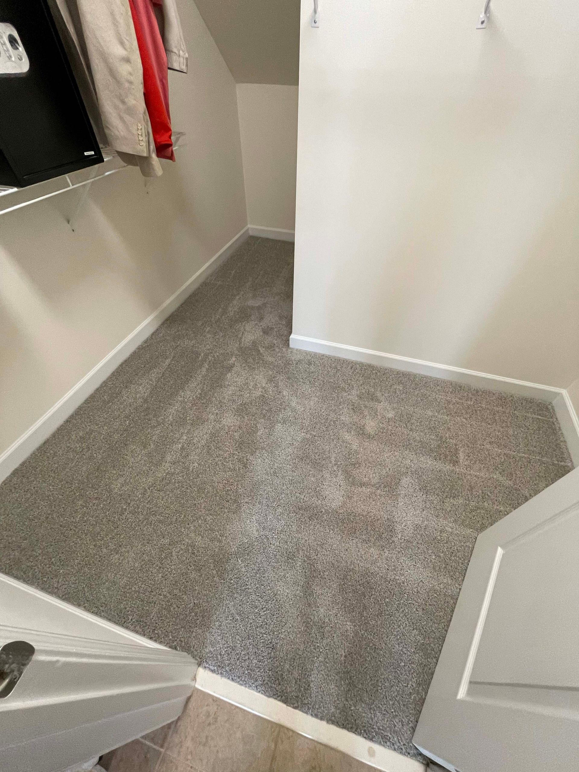 Small room with gray carpet, white walls, and a coat rack.