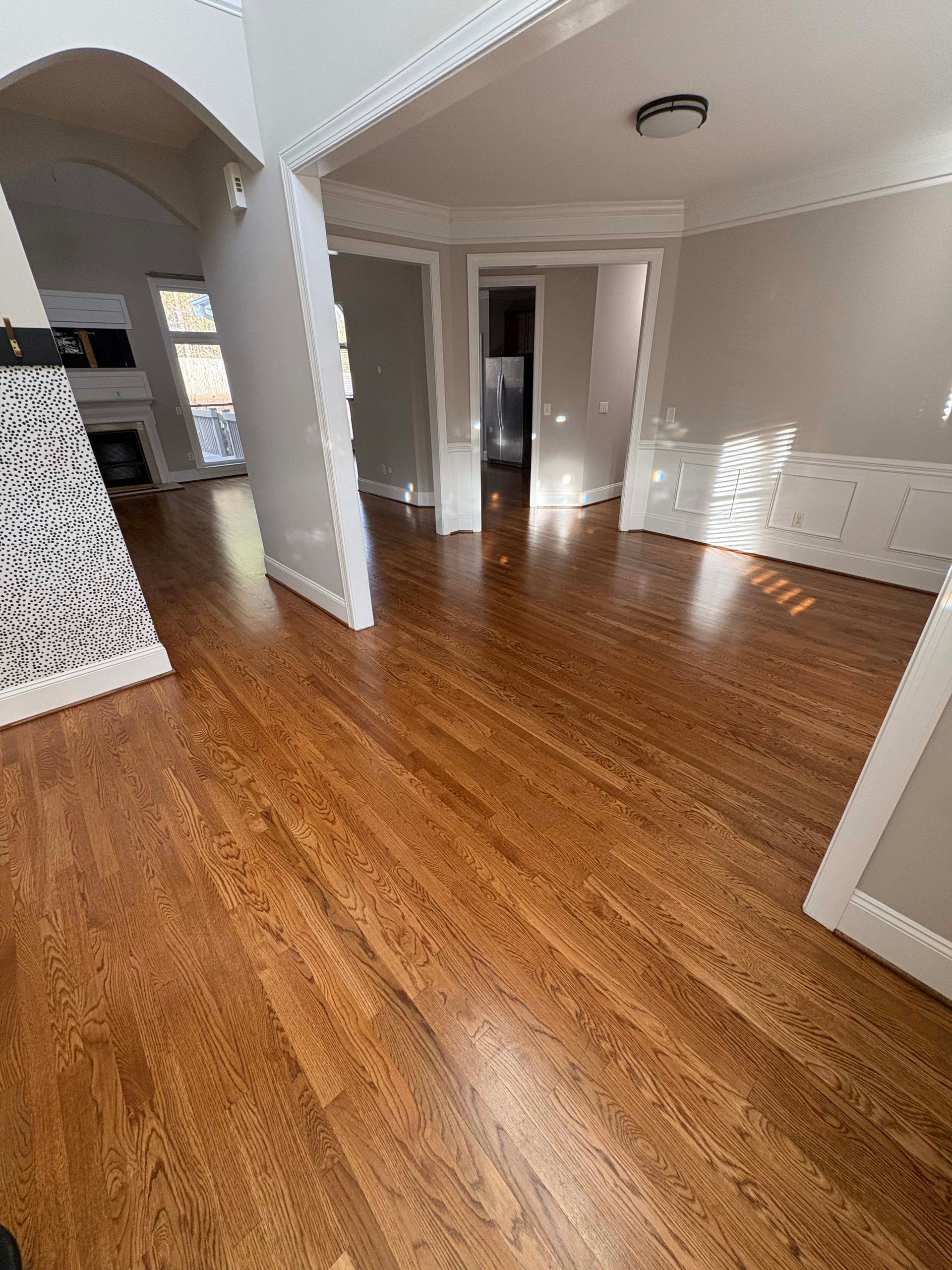 Hardwood floors in a house. Interior view of empty rooms with light gray walls and white trim.
