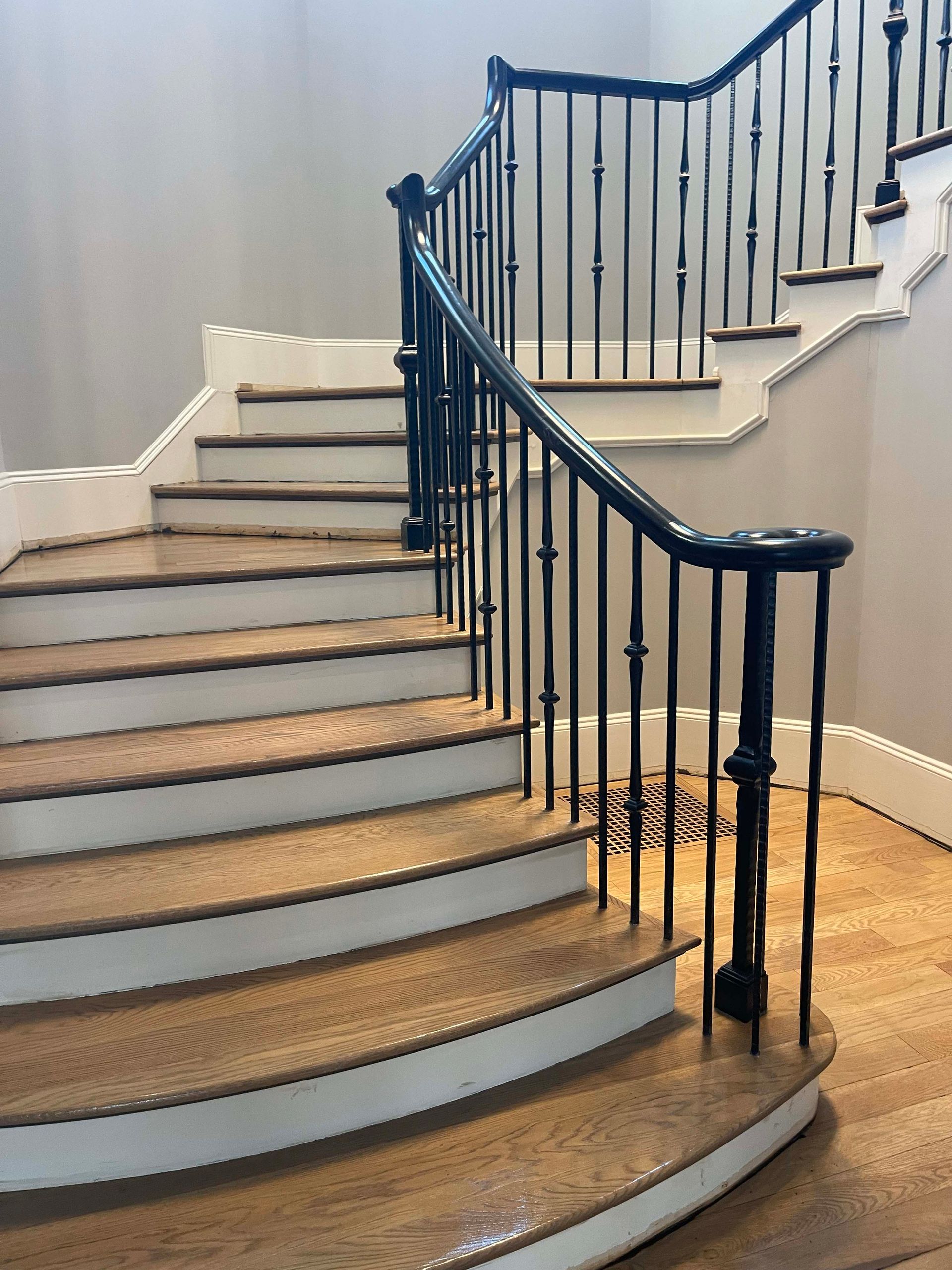 Wooden staircase with black metal railing and white trim.