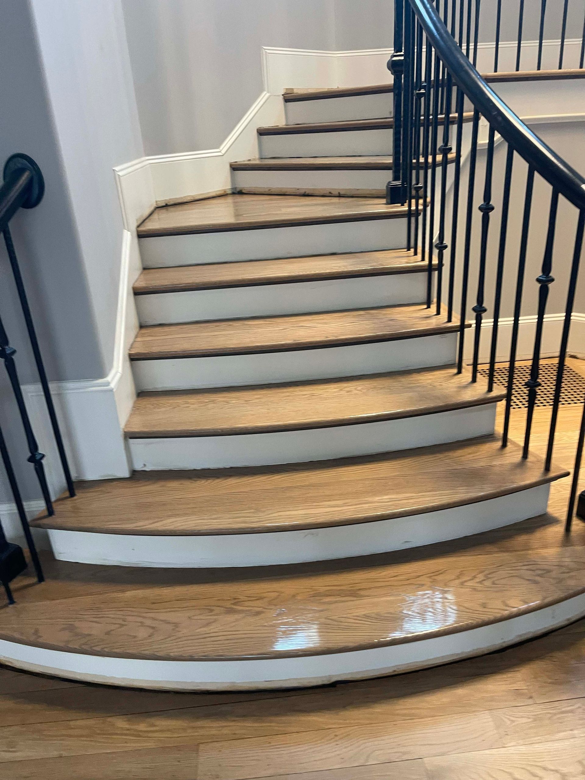 Wooden staircase with black railing and white trim.