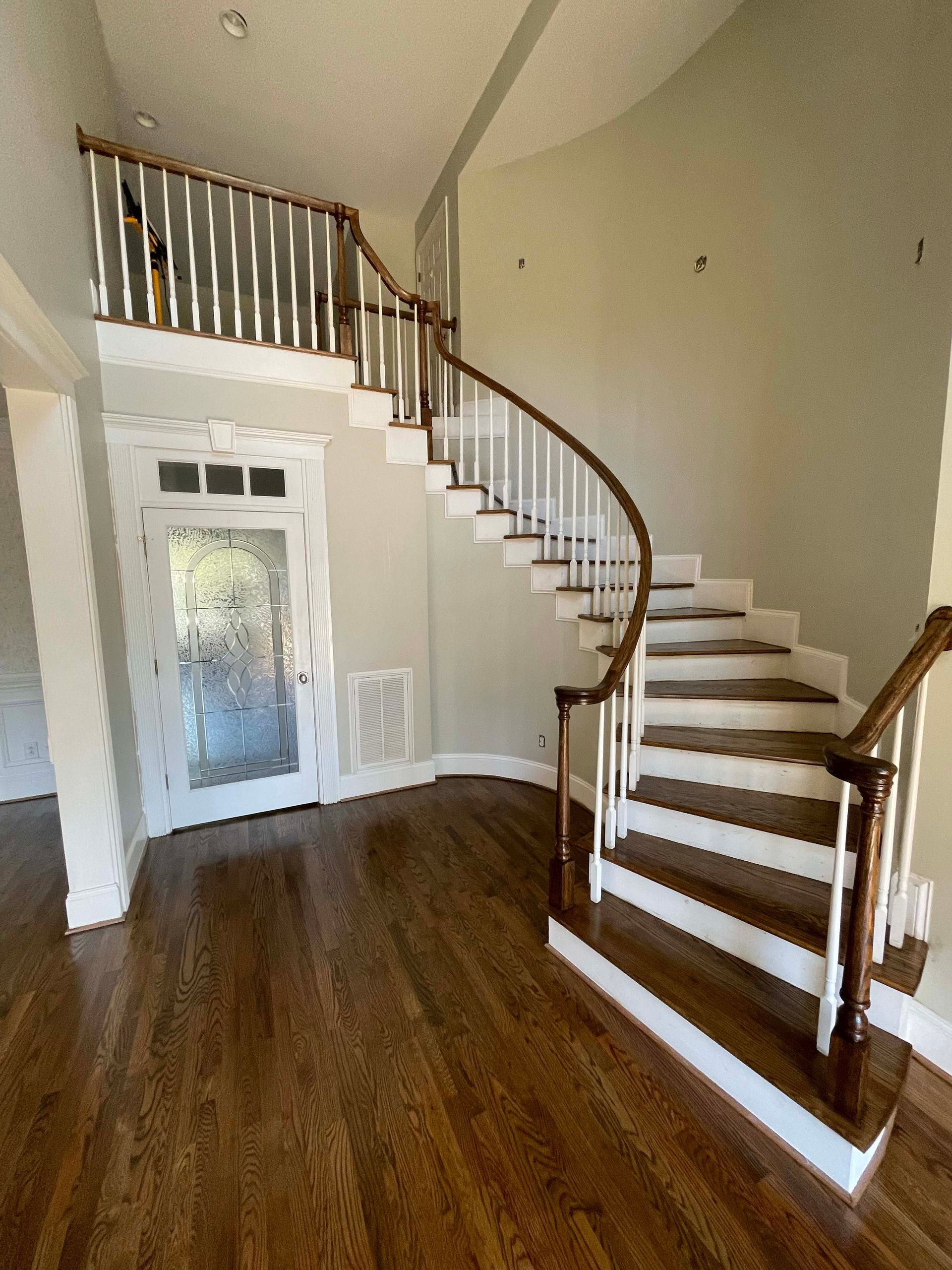 Interior with curved staircase, hardwood floors, and a landing with a railing.