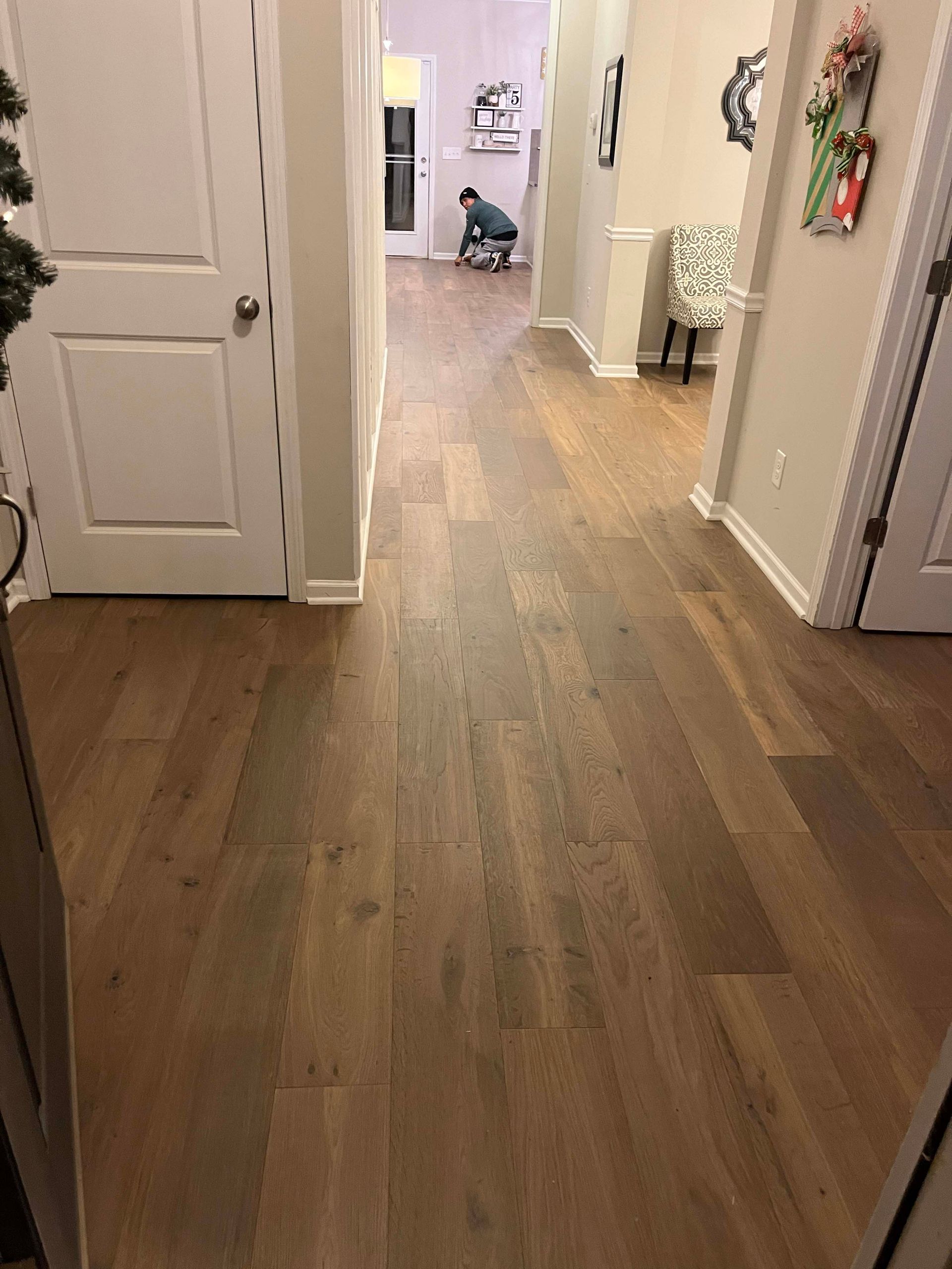Wooden hallway with doors on either side, person in the distance near a decorated entryway.