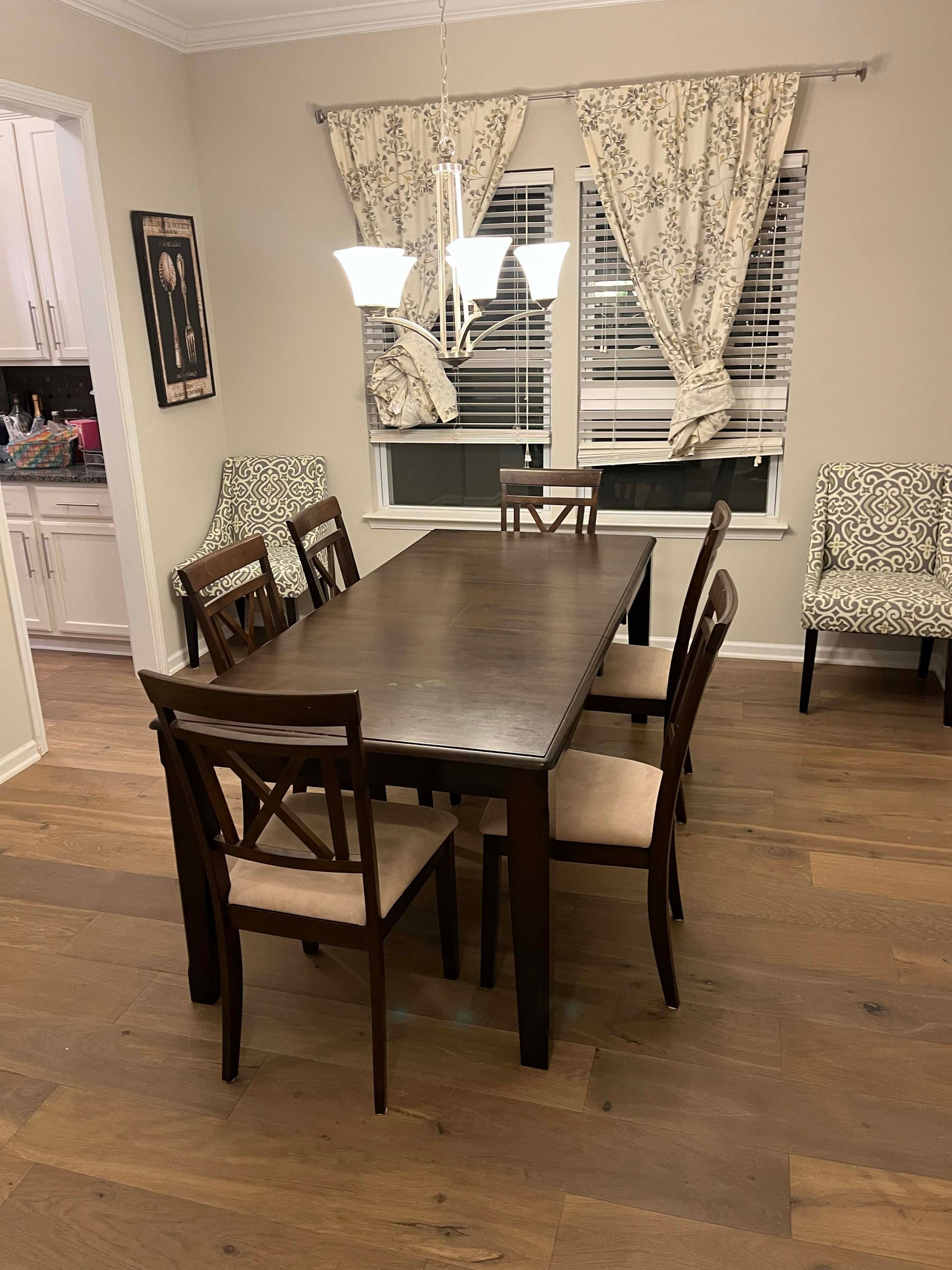 Dining room with a long wooden table, chairs, and window with floral curtains.