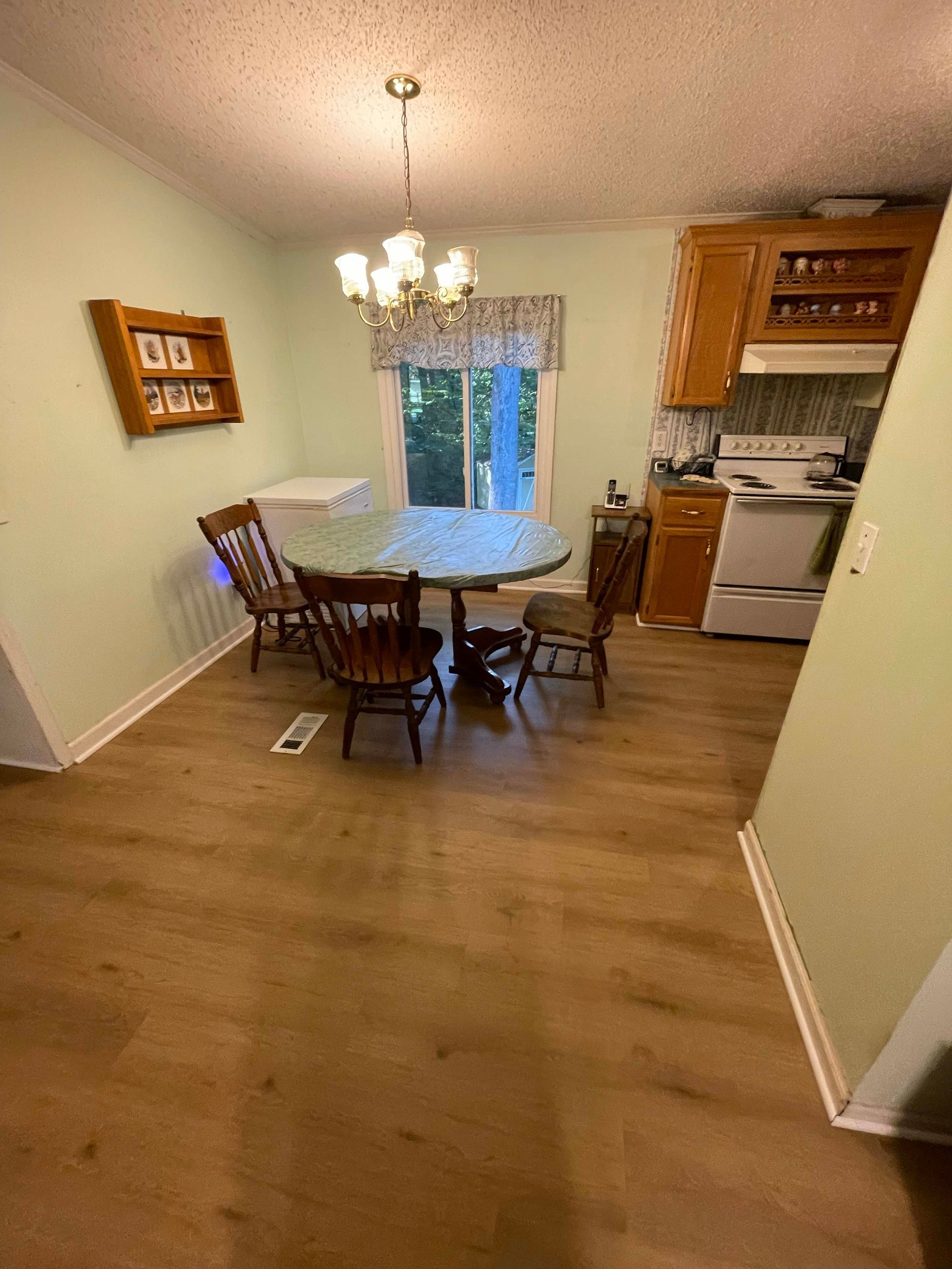 Kitchen with round dining table, four chairs, and light-colored wood cabinets, and hardwood floors.