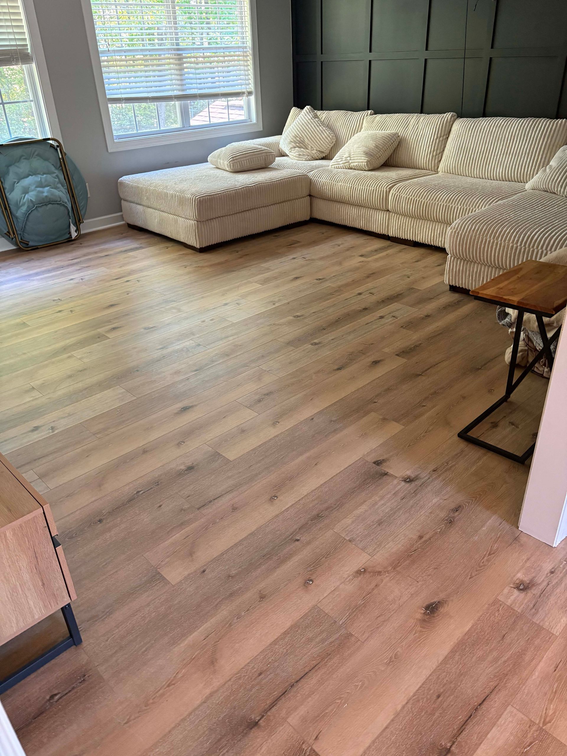 Living room with light wood floors, a large cream sectional sofa, and a side table.