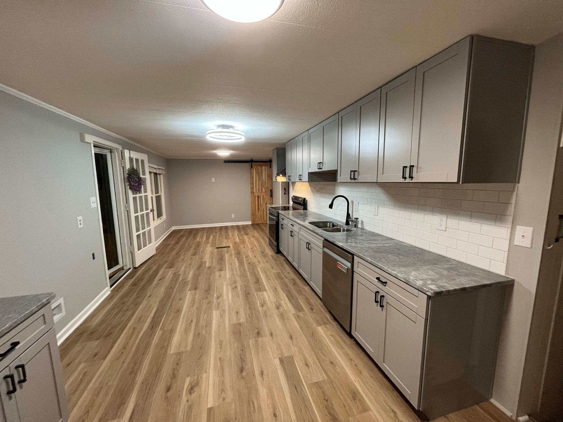 Spacious kitchen with gray cabinets, stainless steel appliances, and wood-look flooring.