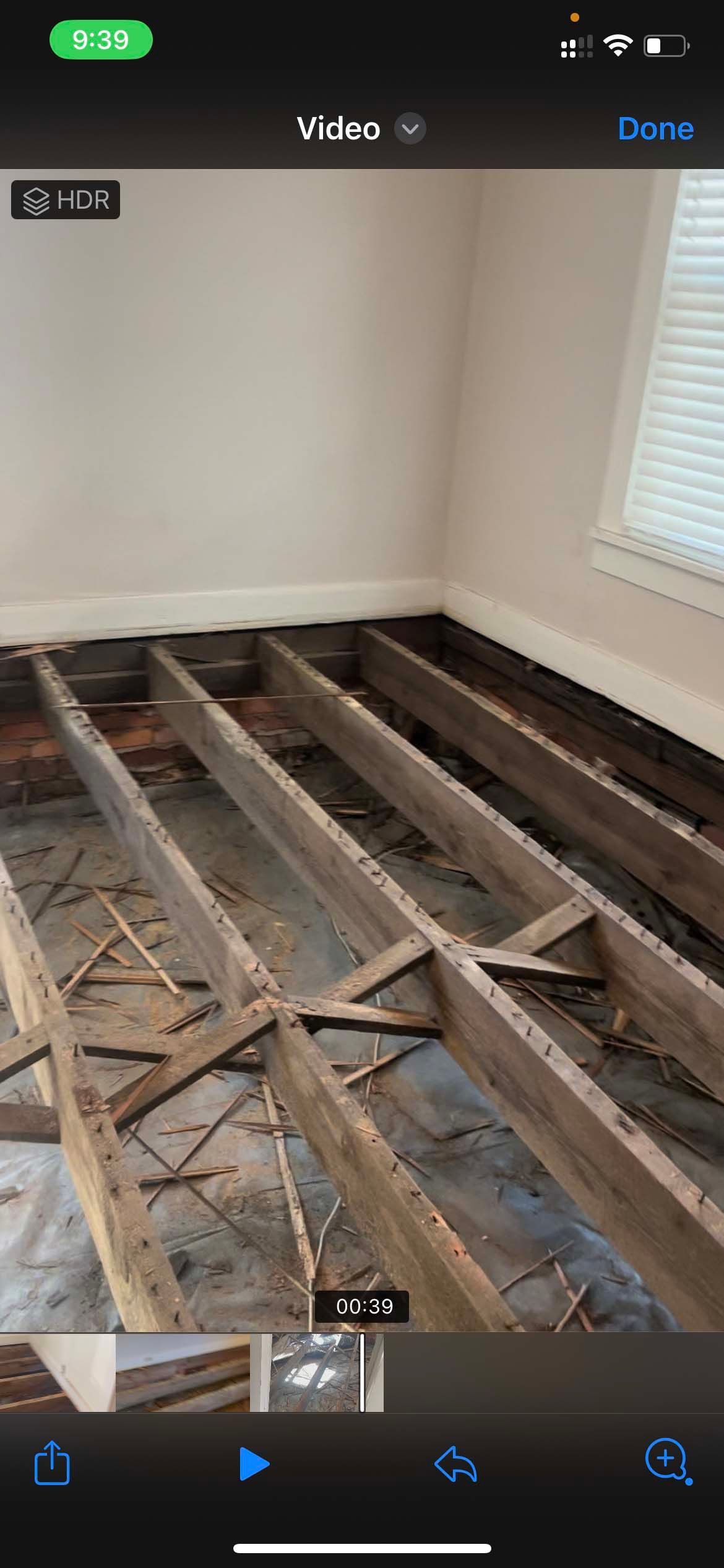 Room with exposed floor joists, indicating floor removal or construction. White walls and a window are visible.