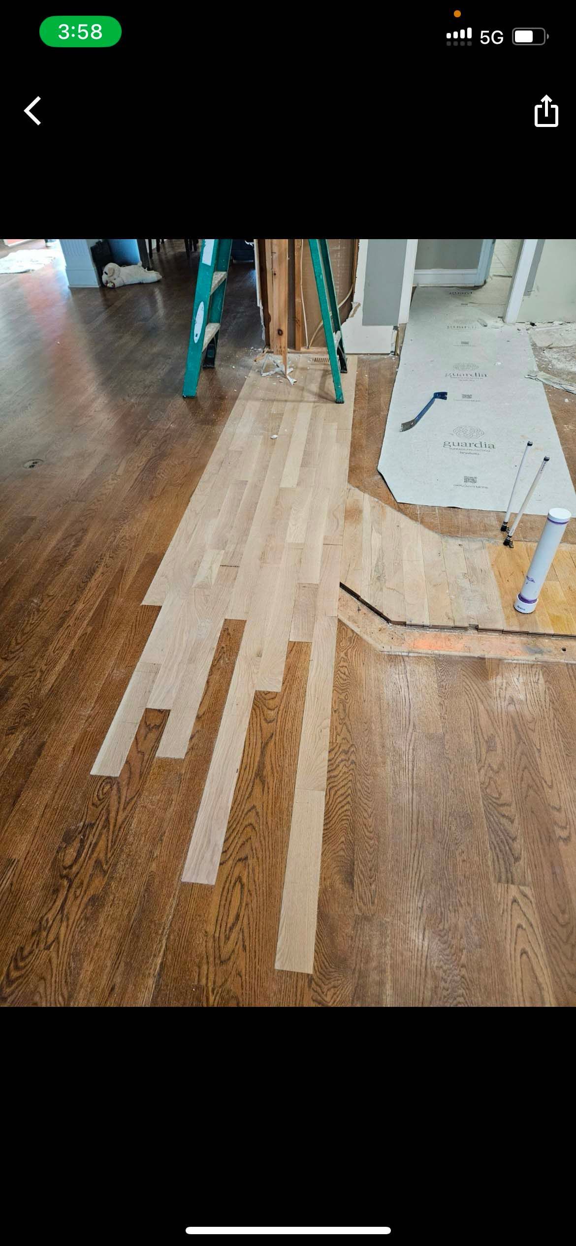 Wooden floor being renovated with new light-colored planks placed over the darker existing floor.