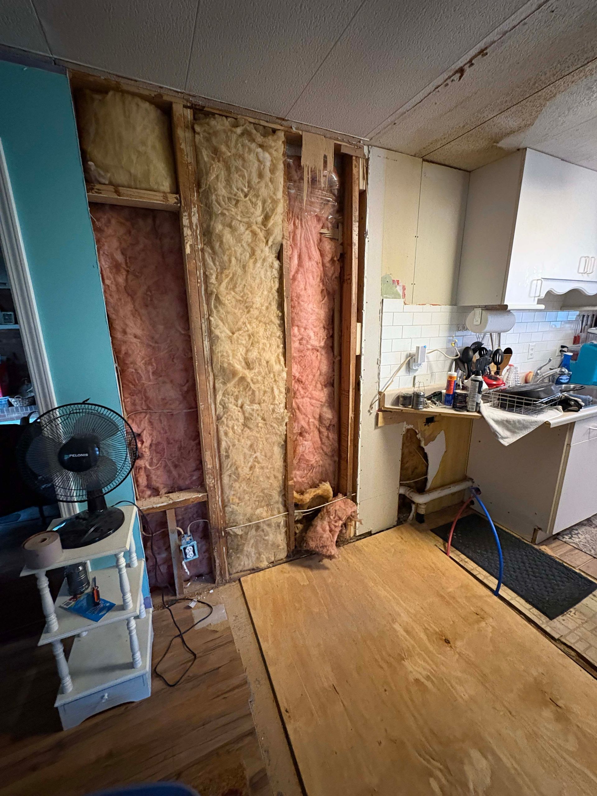 Interior wall with exposed insulation and kitchen counter visible.