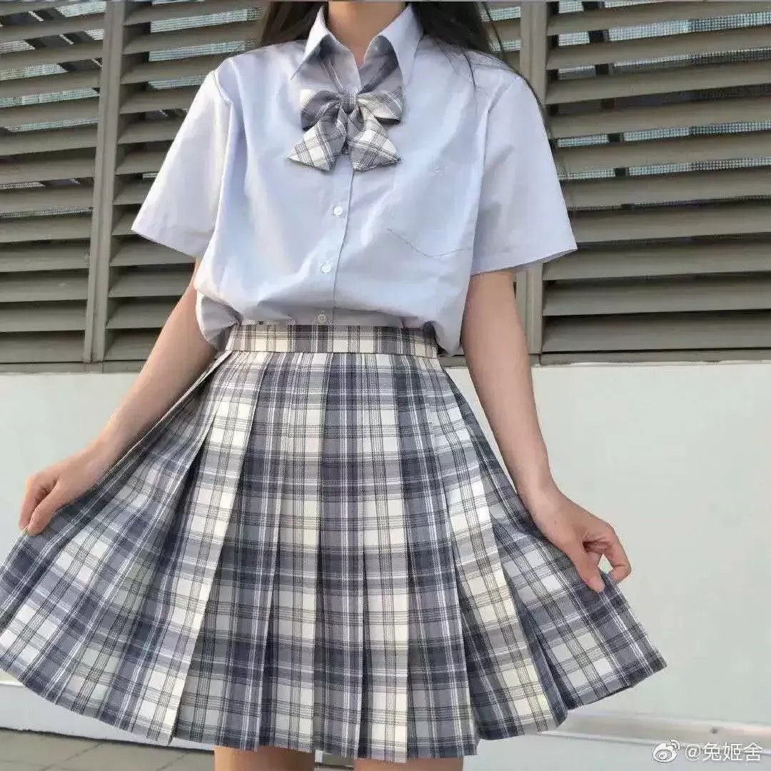 一位穿著藍色襯衫和格子裙的女孩站在一棟建築物前。