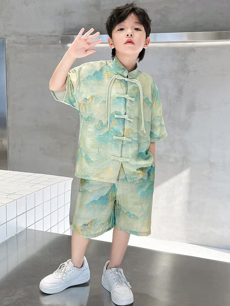 一個穿著綠色襯衫和短褲的小男孩站在桌子上。