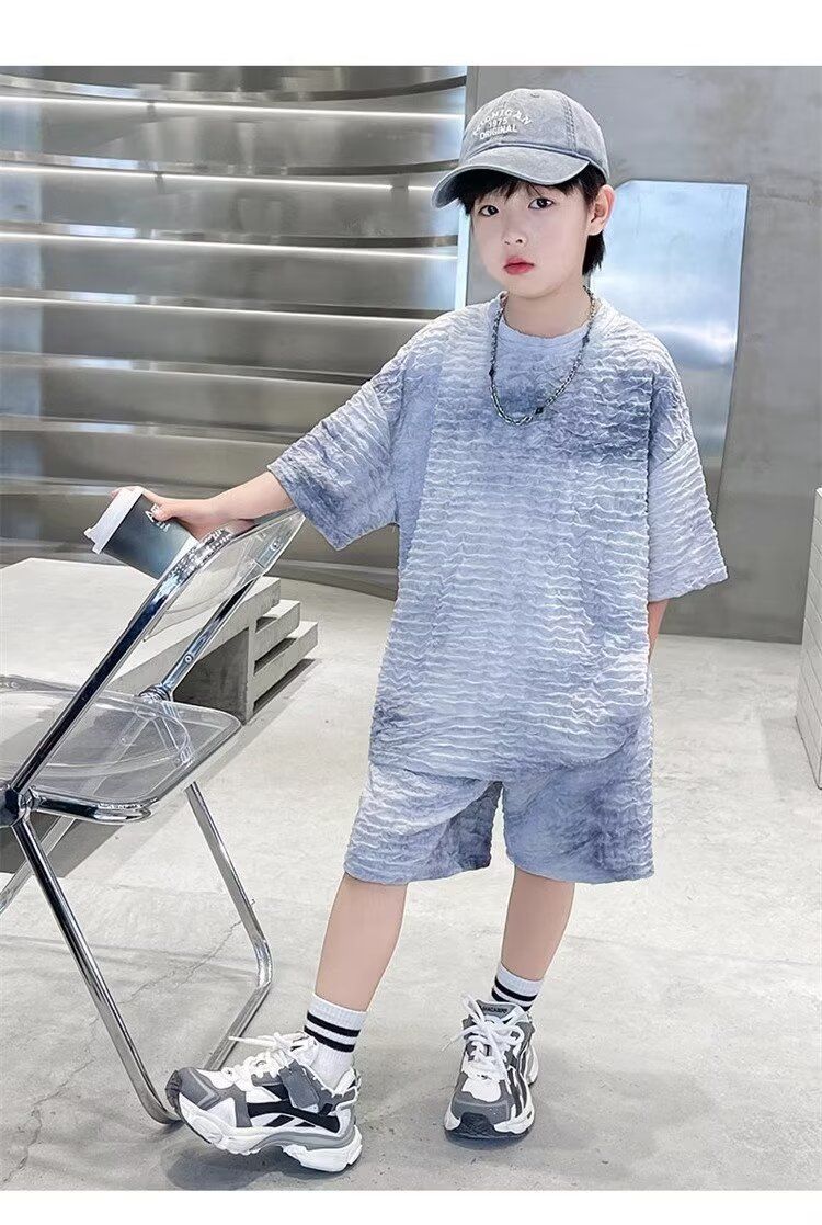 一個戴著帽子、穿著 T 恤的小男孩站在椅子旁邊。