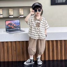 一個戴著墨鏡和帽子的小男孩站在一台筆記型電腦前。