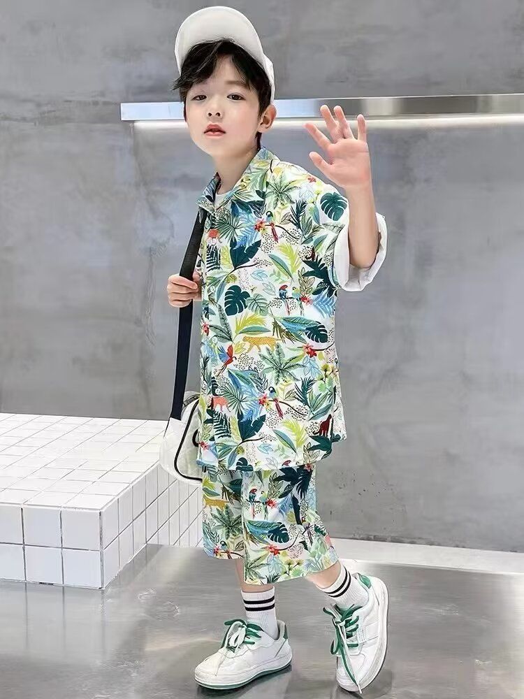 一個穿著夏威夷襯衫和短褲的小男孩站在瓷磚地板上。