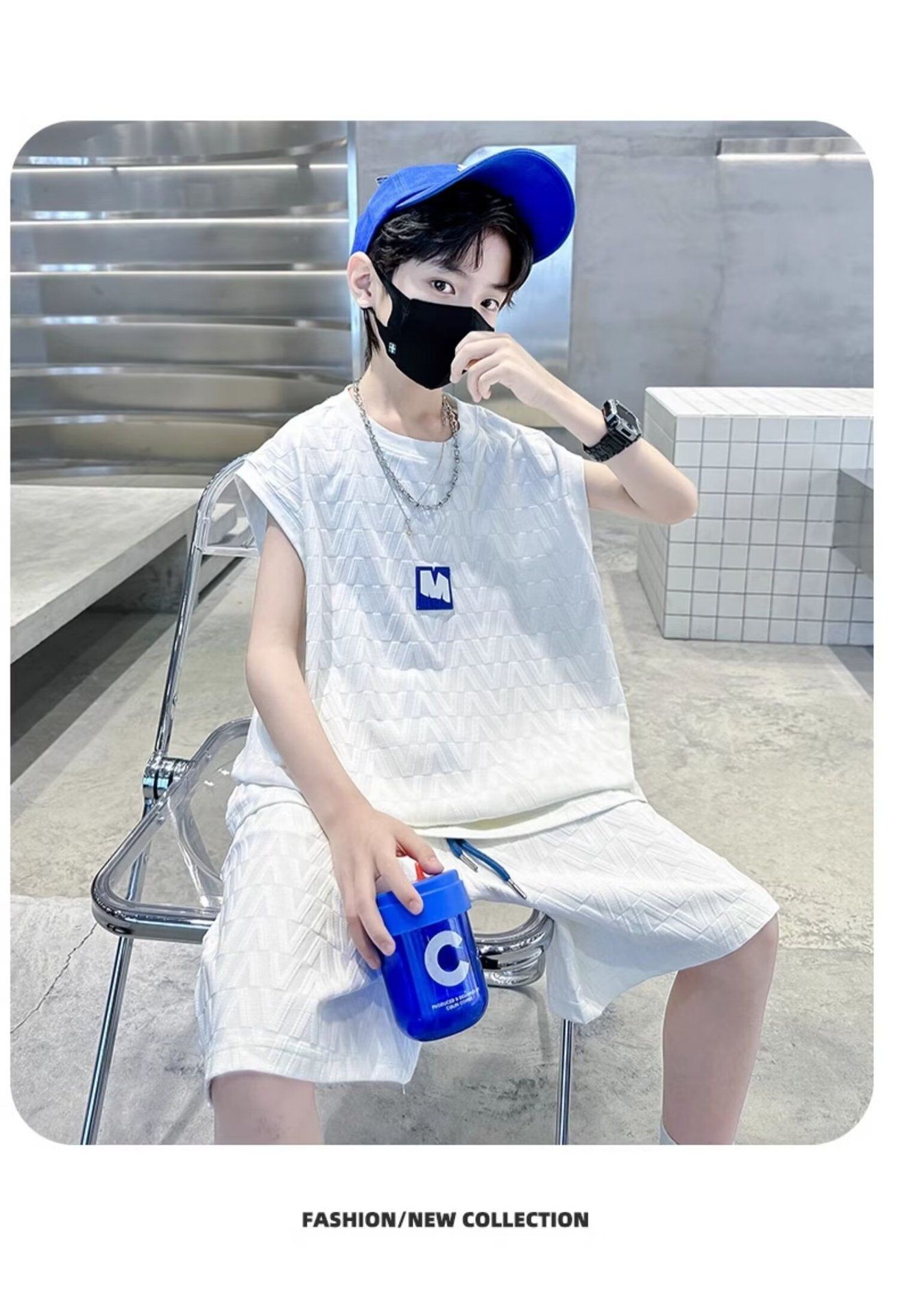 一個戴著口罩和藍色帽子的小男孩坐在椅子上。
