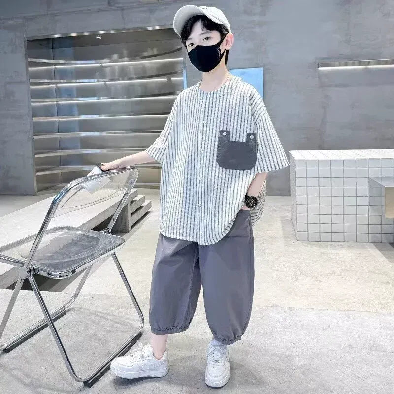 一個戴著口罩、穿著條紋襯衫的小男孩站在椅子旁。