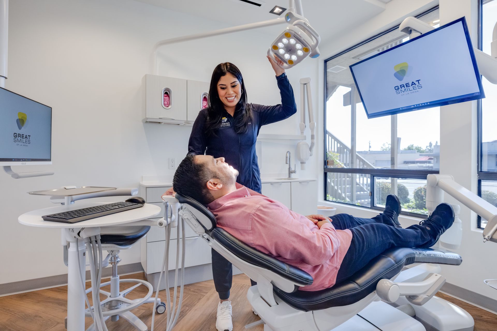 A woman is standing next to a man in a dental chair