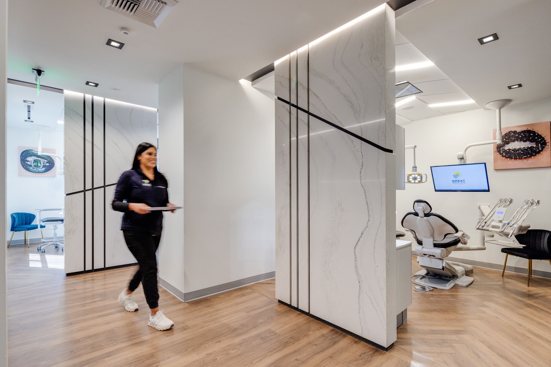 A woman is walking through a dental office holding a clipboard.