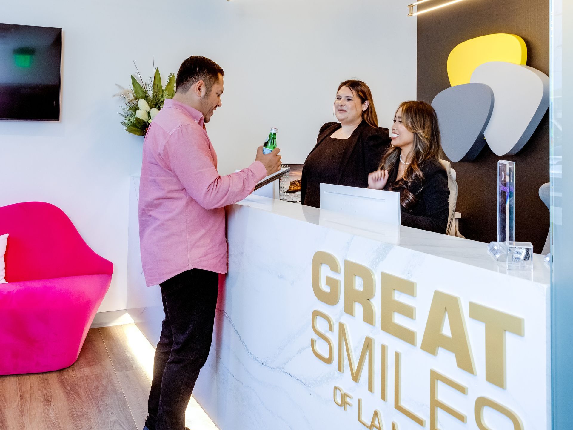 A man in a pink shirt is standing at a great smiles of la mesa reception desk