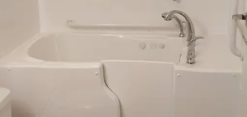 A modern bathroom with two white wall-mounted sinks, a glass-enclosed shower, and decorative pebble-tiled walls.