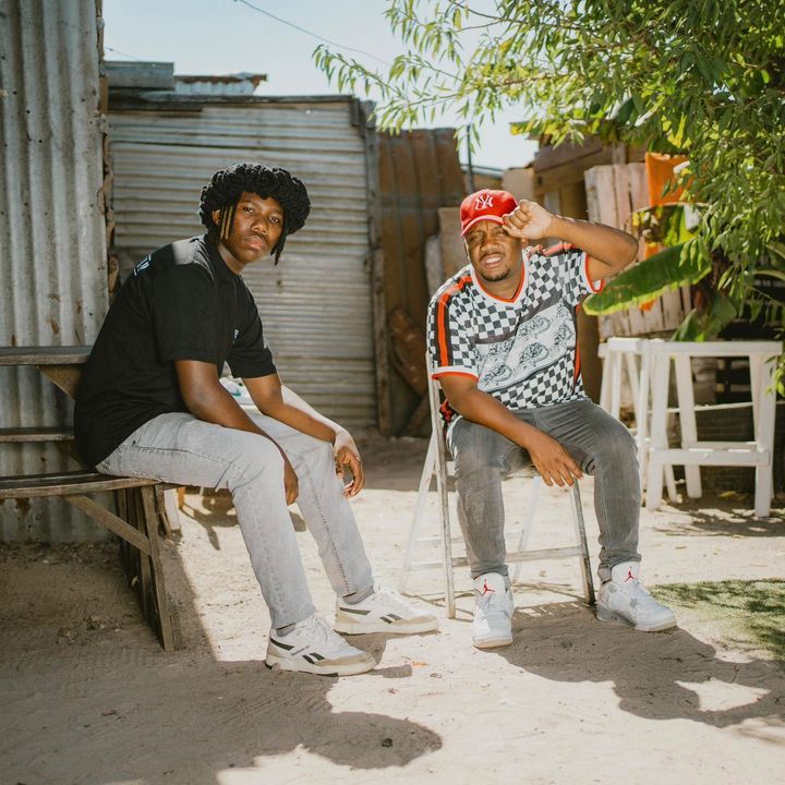 Three men are standing next to each other on a white background.