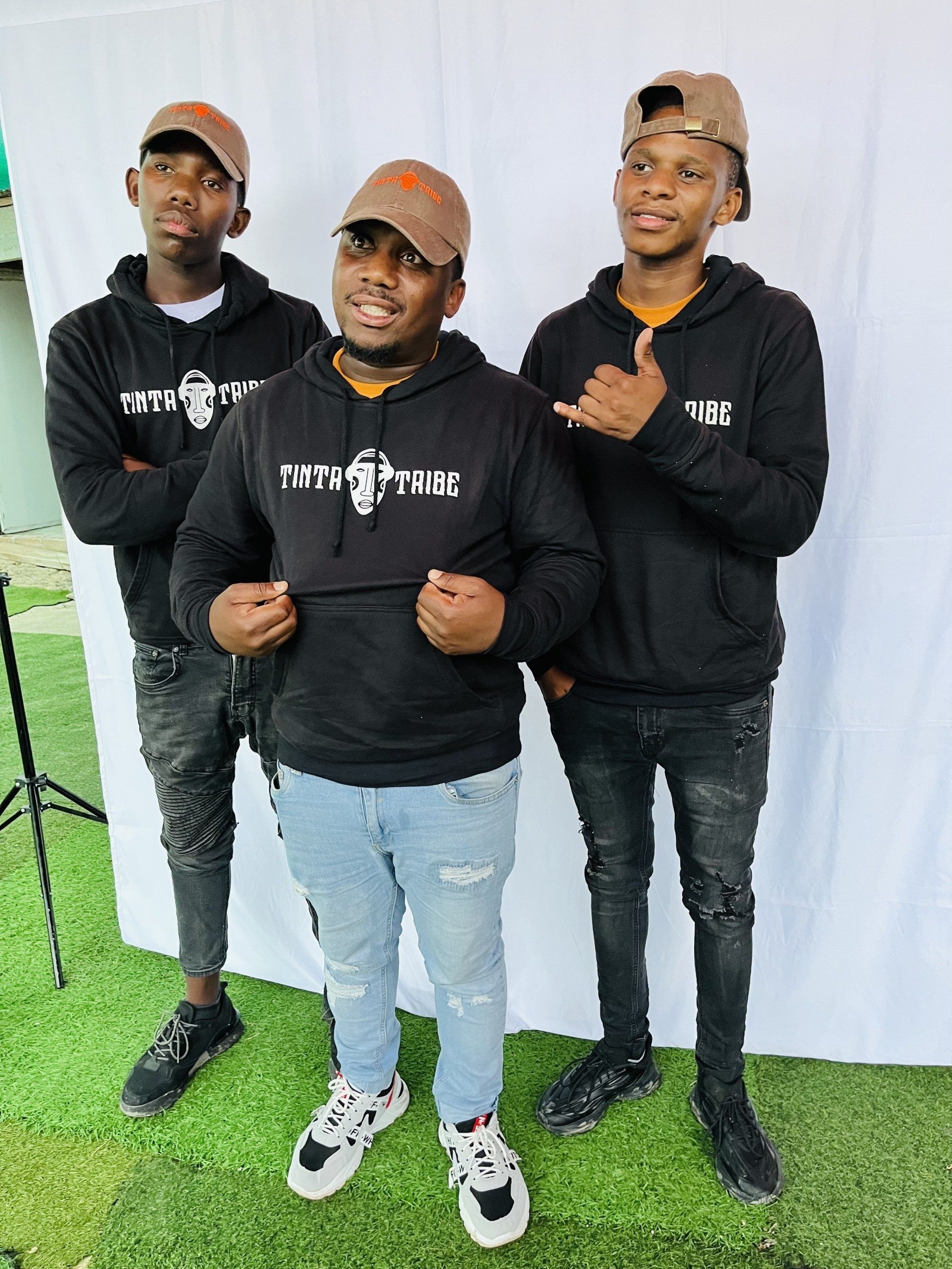 Three men are standing next to each other in front of a white curtain.
