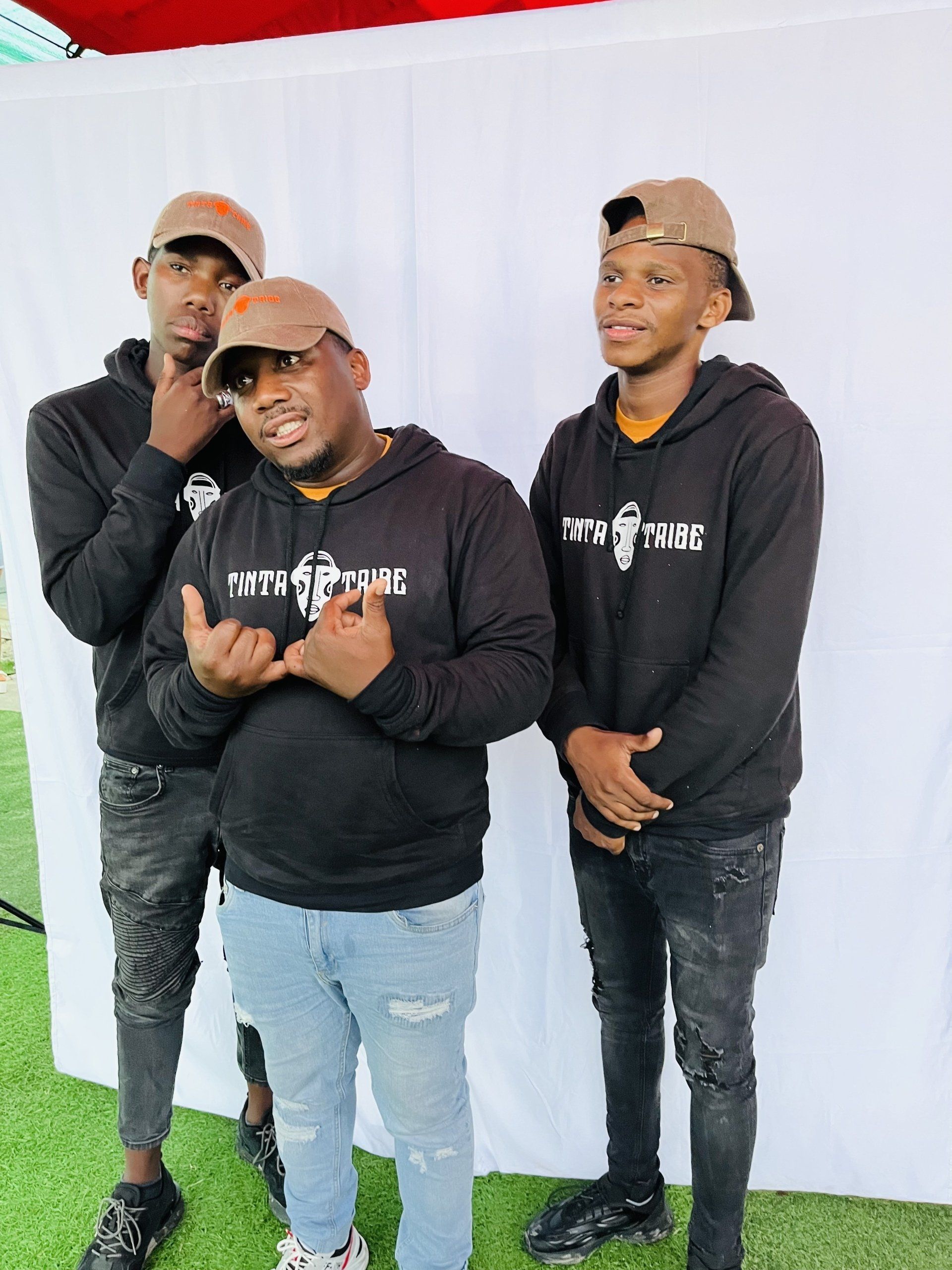 Three men are standing next to each other in front of a white wall.